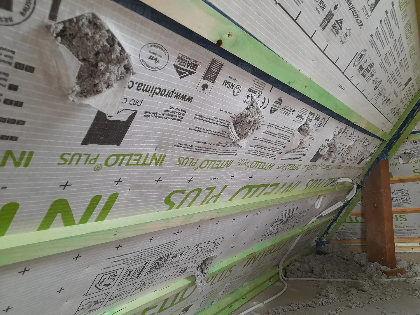 Schuin dak met dampremmende folie en ingeblazen Isoproc cellulose achter de inblaasopeningen